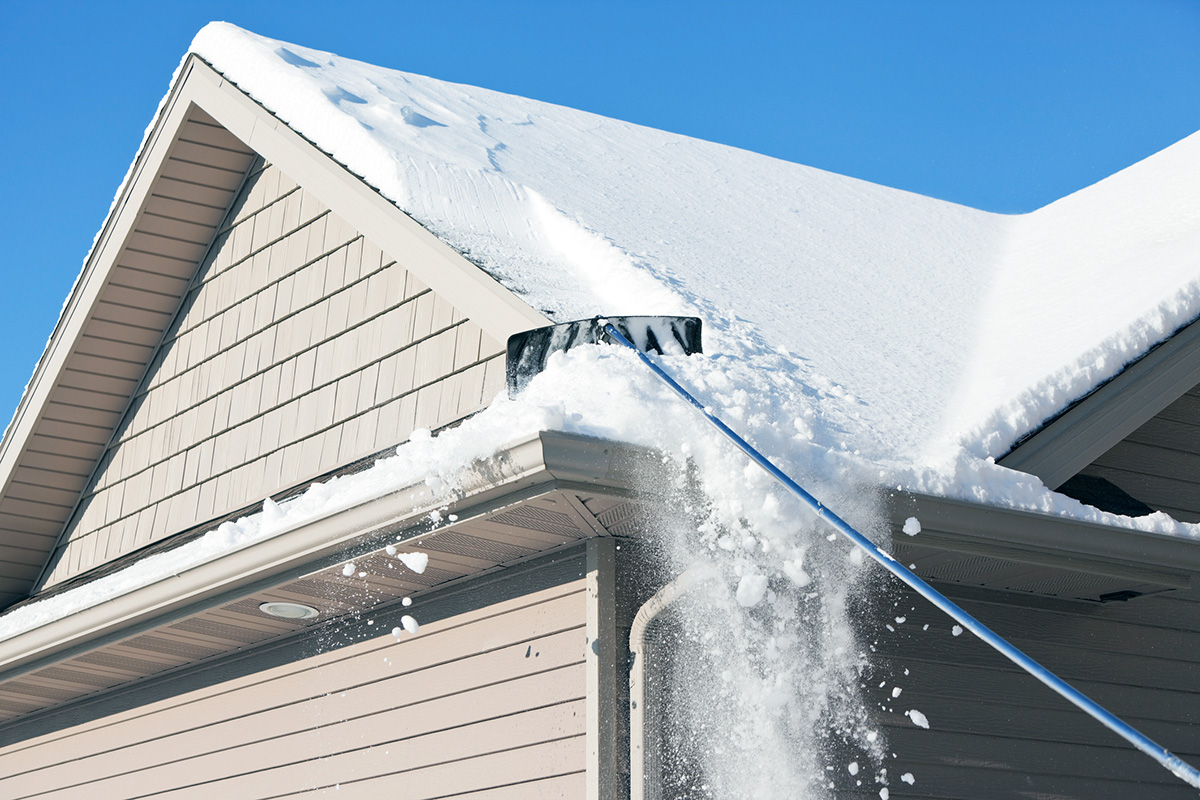 A roof rake is being used to remove snow from a winter roof.
