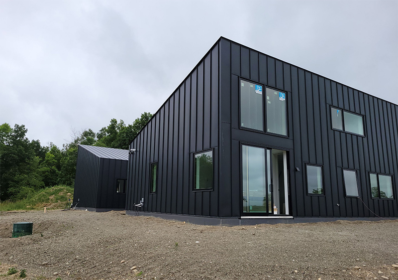 Square modern home featuring a standing seam metal roof and matching metal siding for a seamless look
