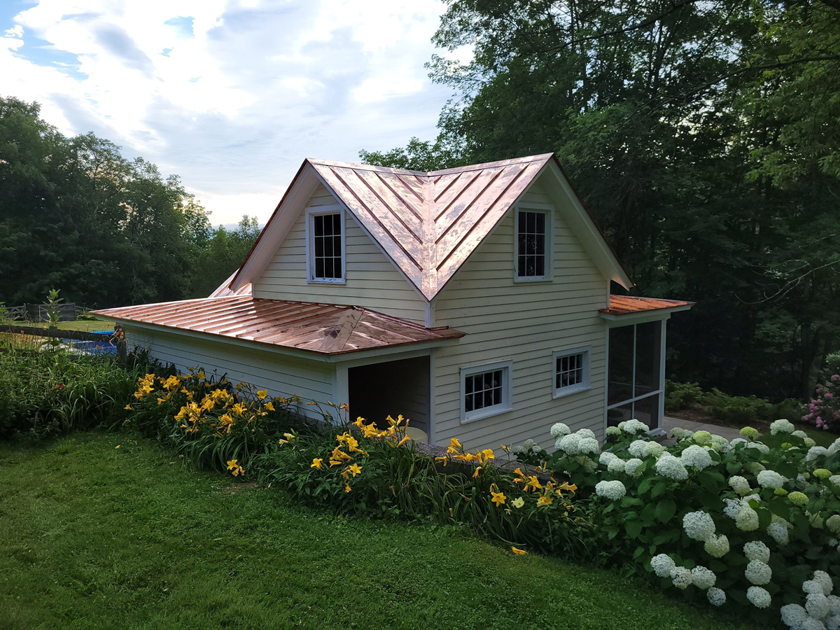 light yellow house with a copper roof
