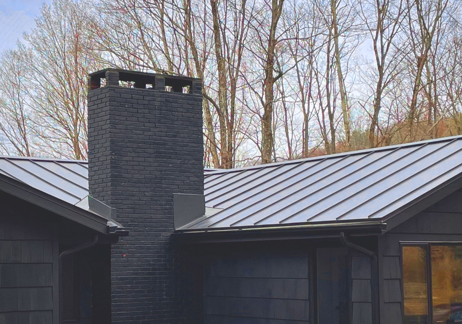 Galvalume metal roof with a brick chimney, highlighting the seamless integration of metal roofing with traditional home features.