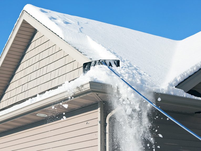 A roof rake is being used to remove snow from a winter roof.